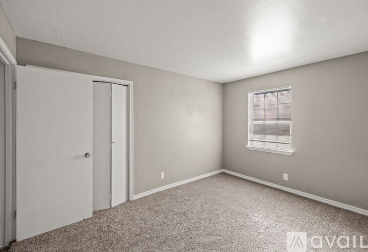 A room with a carpeted floor, a window with blinds, and a door.