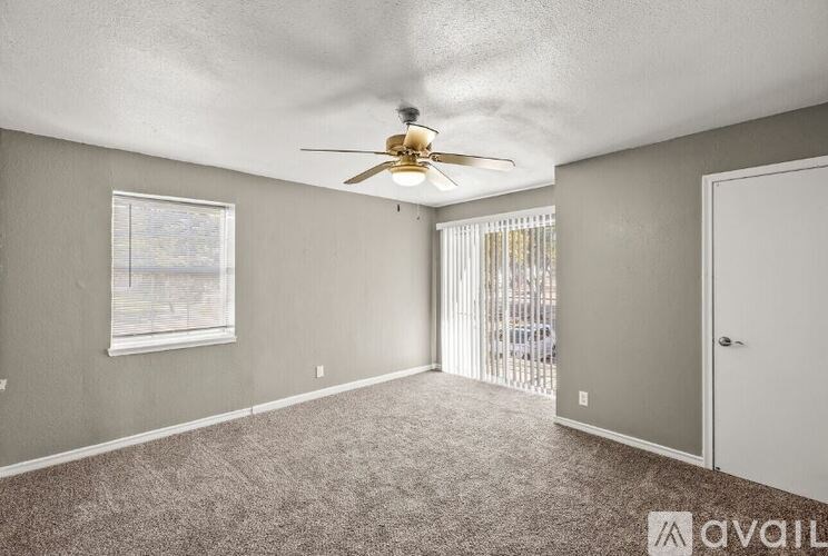 A room with a ceiling fan and carpeted floor.