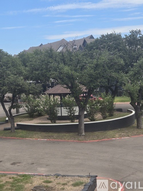 A tree-lined street with a gazebo in the middle.