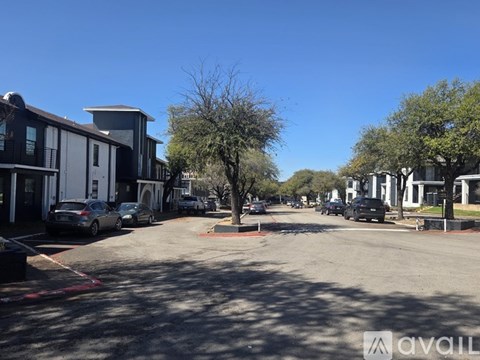 A sunny day in a parking lot with cars and buildings.