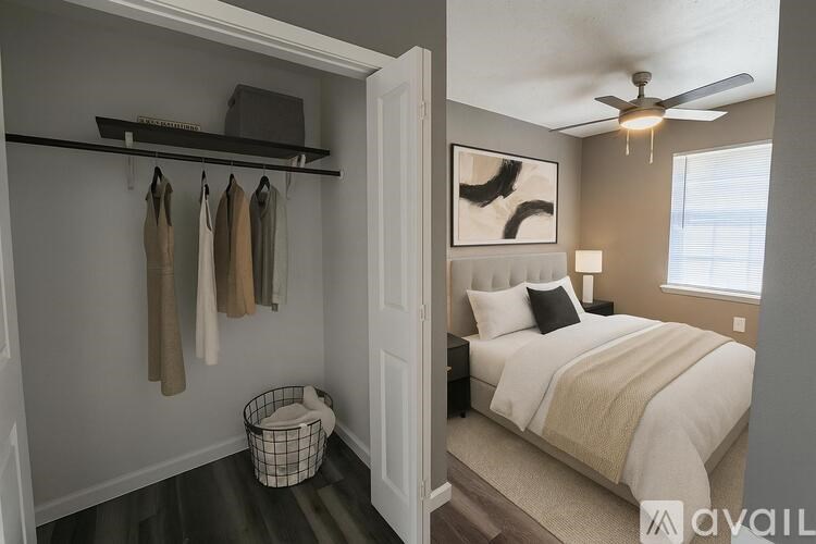 A spacious room with wooden flooring and a large window with blinds.