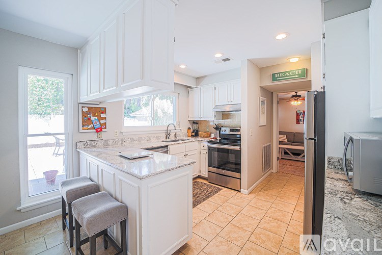 A kitchen with white cabinets and a marble countertop.
