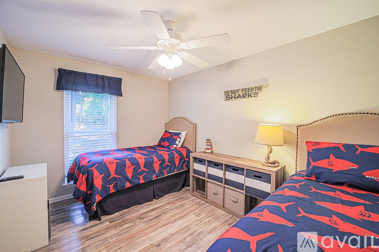 A bedroom with two beds, one with a shark pattern, and a ceiling fan.