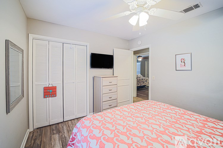 A bedroom with a bed, dresser, and a TV.