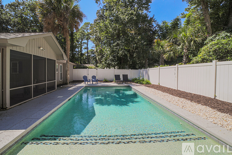 A pool surrounded by a white fence and trees.