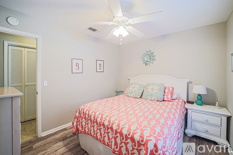 A bedroom with a bed, nightstand, and a ceiling fan.