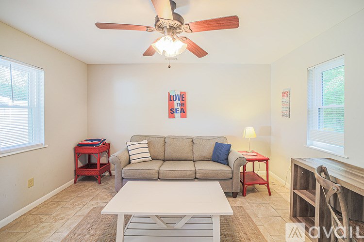 A living room with a couch, a table, and a fan.