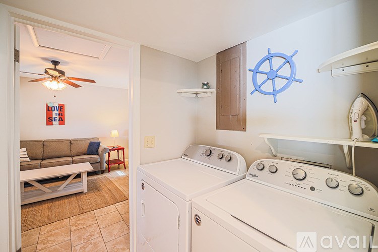 A laundry room with a washer and dryer and a ship wheel decoration on the wall.