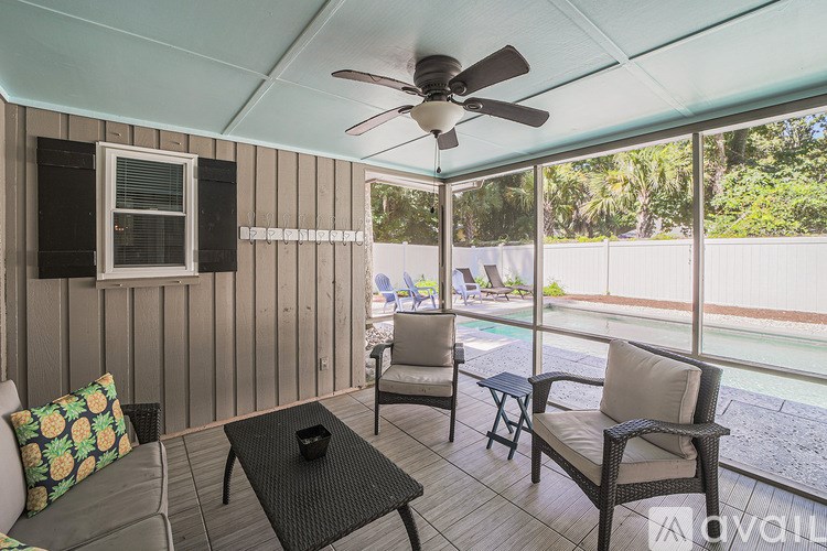 A patio with a ceiling fan and chairs.