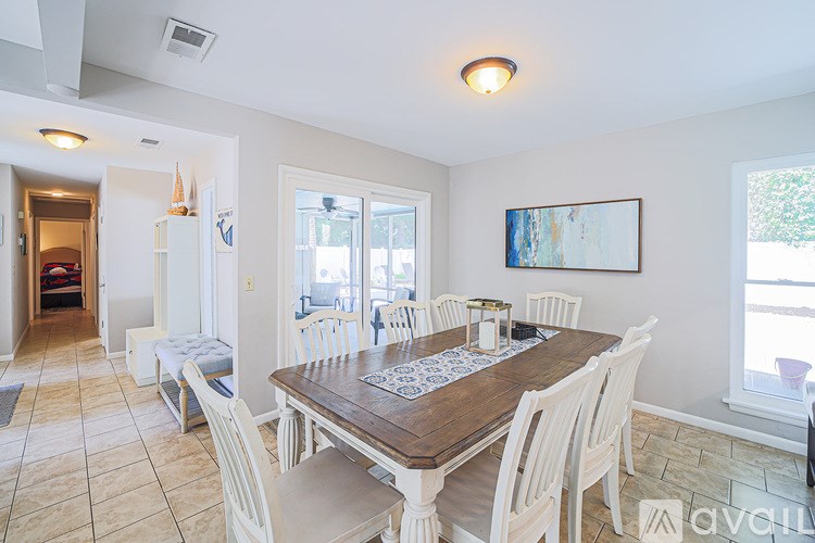 A dining room with a wooden table surrounded by white chairs.