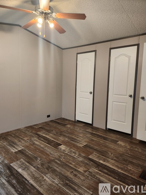 A room with a ceiling fan and wooden flooring.