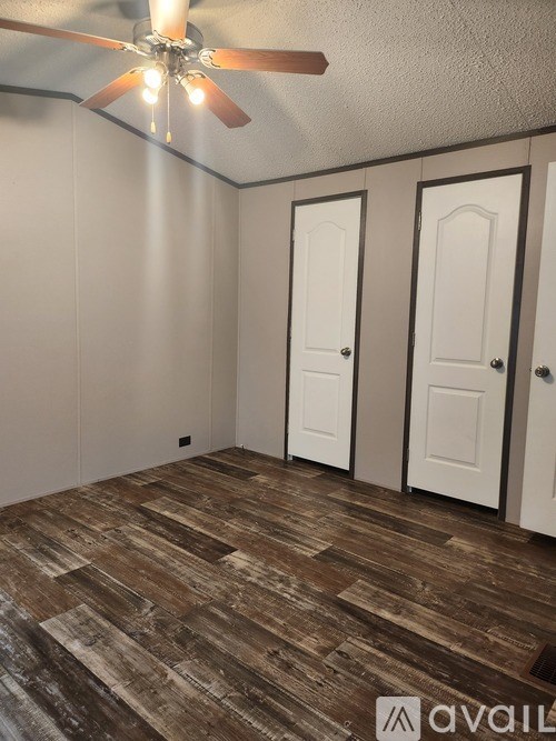 A room with a ceiling fan and wooden flooring.