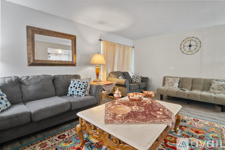 A living room with a grey couch, a wooden coffee table, and a mirror on the wall.