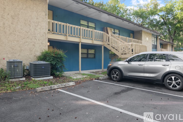 A silver car is parked in a parking lot in front of a blue building.