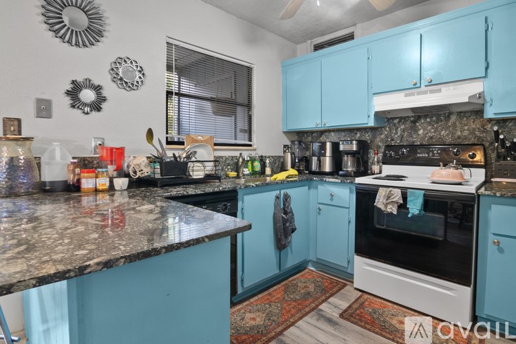 A kitchen with a black granite countertop and blue cabinets.