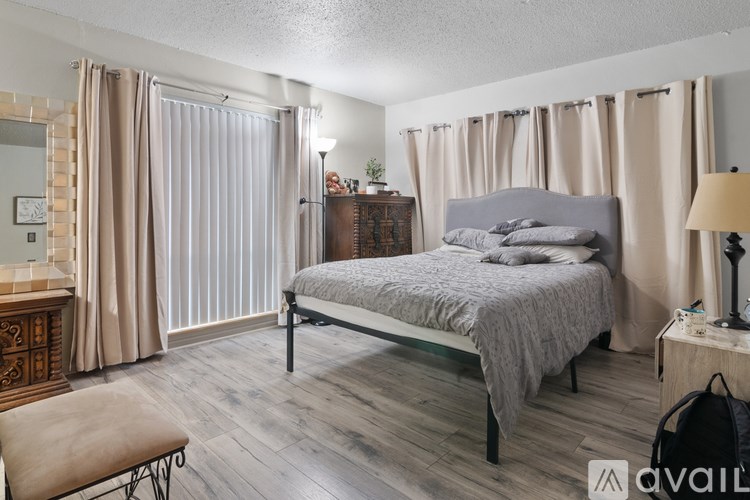 A bedroom with a large bed, a bench, and a dresser with a mirror.