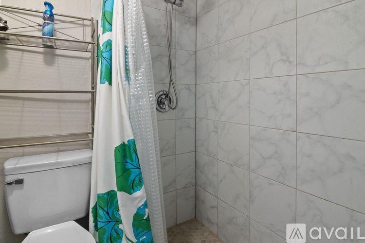 A white toilet with a white and green shower curtain in a bathroom.