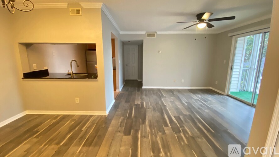 A spacious room with wooden flooring and a ceiling fan.