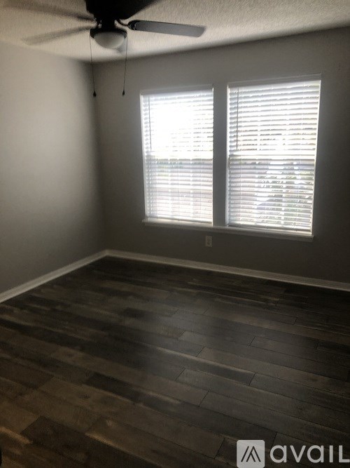 A room with a ceiling fan and a window with blinds.