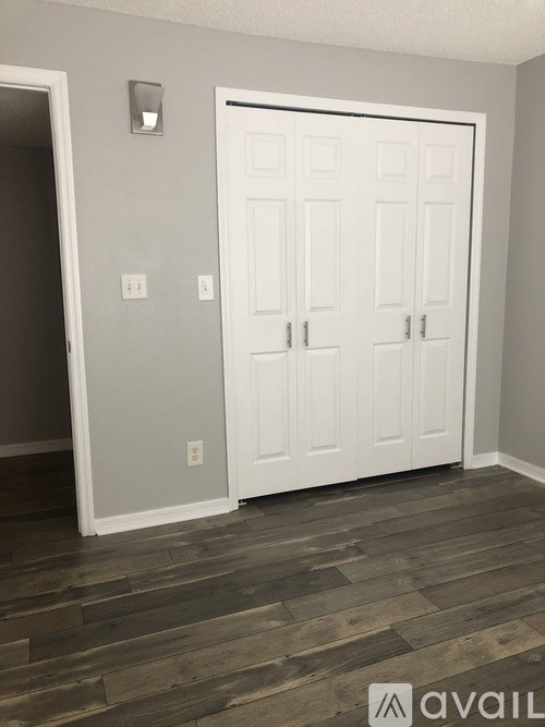 A white door is in a room with wooden flooring.