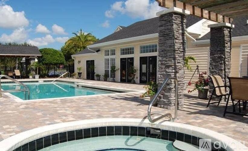 A pool with a stone pillar and a house in the background.