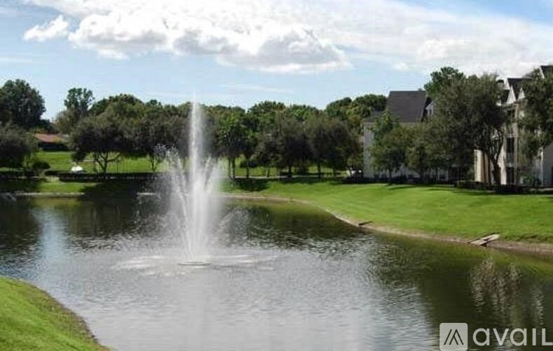 A fountain in the middle of a pond in a park.
