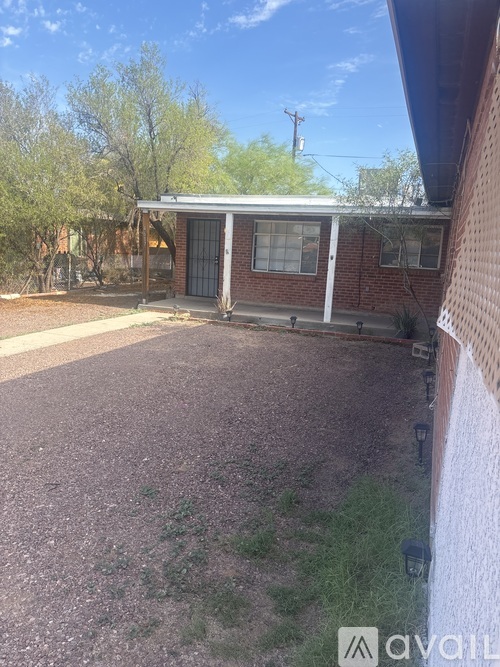 A house with a brick wall and a gravel driveway.