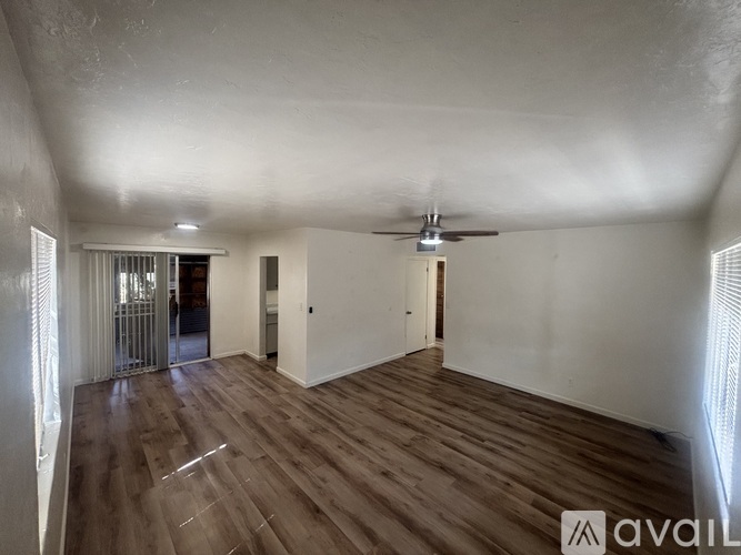 A spacious room with wooden flooring and a ceiling fan.