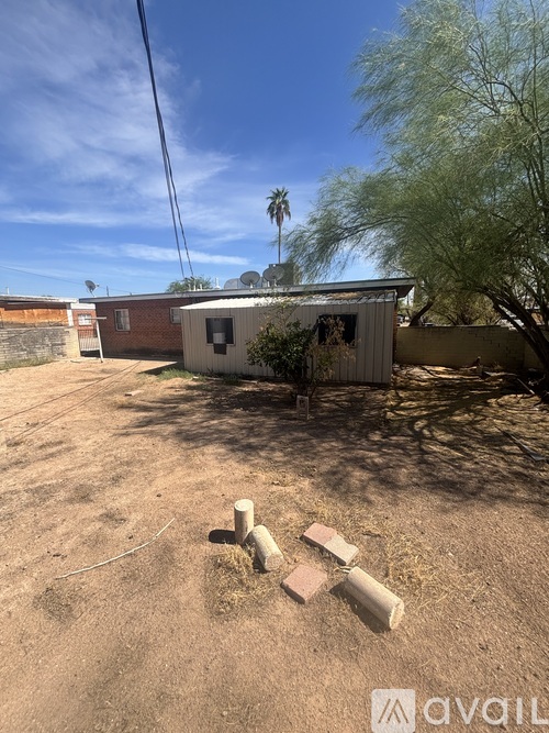A backyard with a dirt ground and a small building.