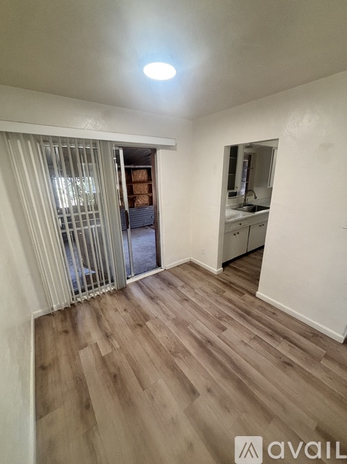 A room with wooden flooring and a sliding door leading to a balcony.