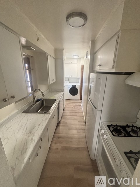 A kitchen with white cabinets and a marble countertop.
