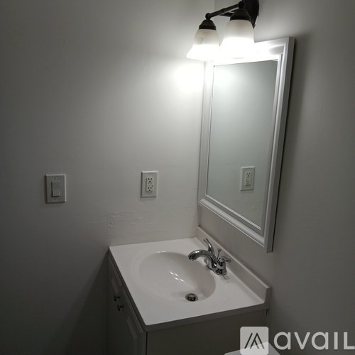 A white sink under a mirror with a light above it.