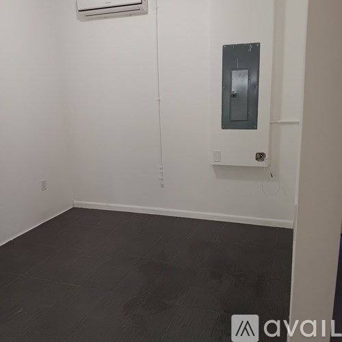 A room with a grey floor and a grey wall with a white air conditioner unit.