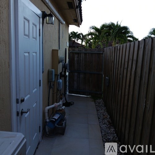 A white door is on the left of a concrete walkway.