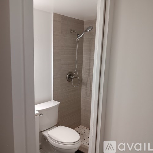 A white toilet with a white lid is in a bathroom with a shower.