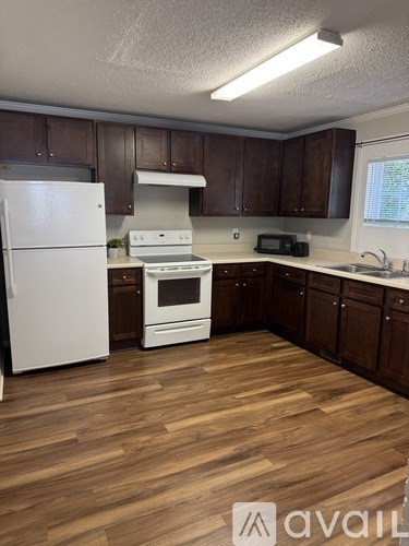 A kitchen with white appliances and wooden floors.