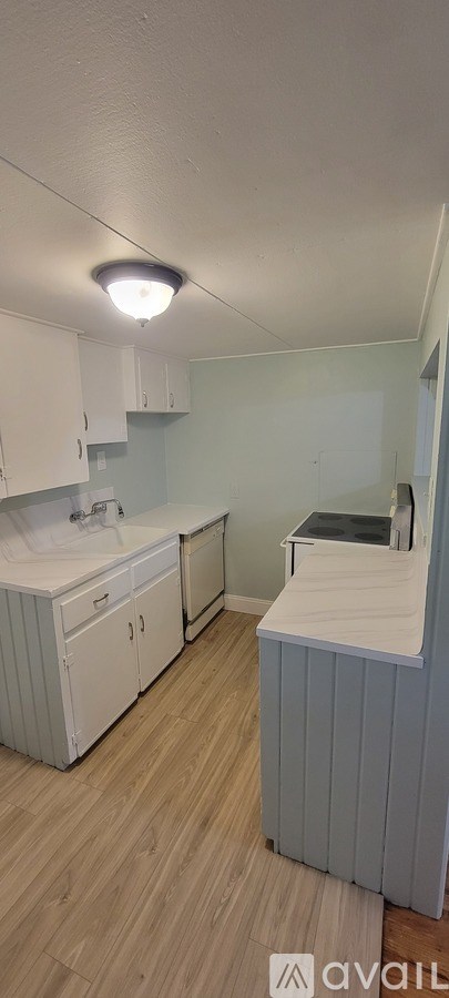 A kitchen with white cabinets and a wooden floor.