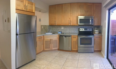 A kitchen with wooden cabinets and a stainless steel refrigerator.