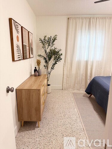 A bedroom with a bed, a wooden cabinet, and a plant.