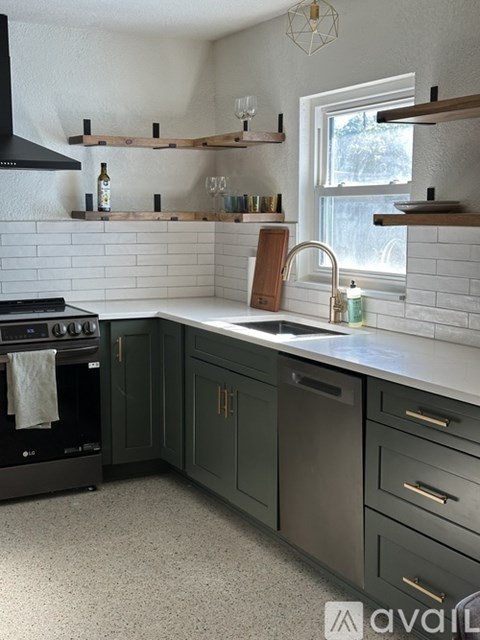 A kitchen with a black oven and green cabinets.