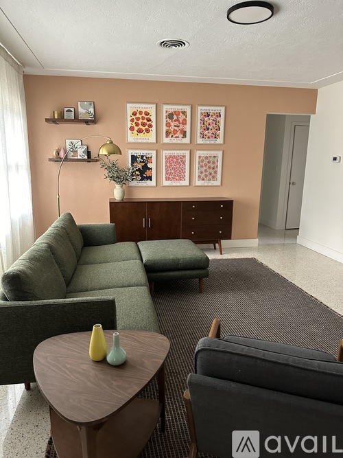 A living room with a grey sofa, a green armchair, a wooden coffee table and a brown cabinet.