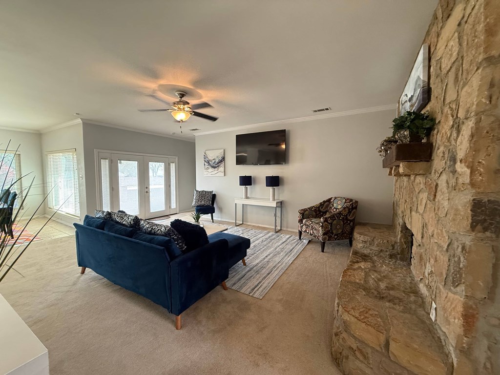 A living room with a blue couch and a stone fireplace.