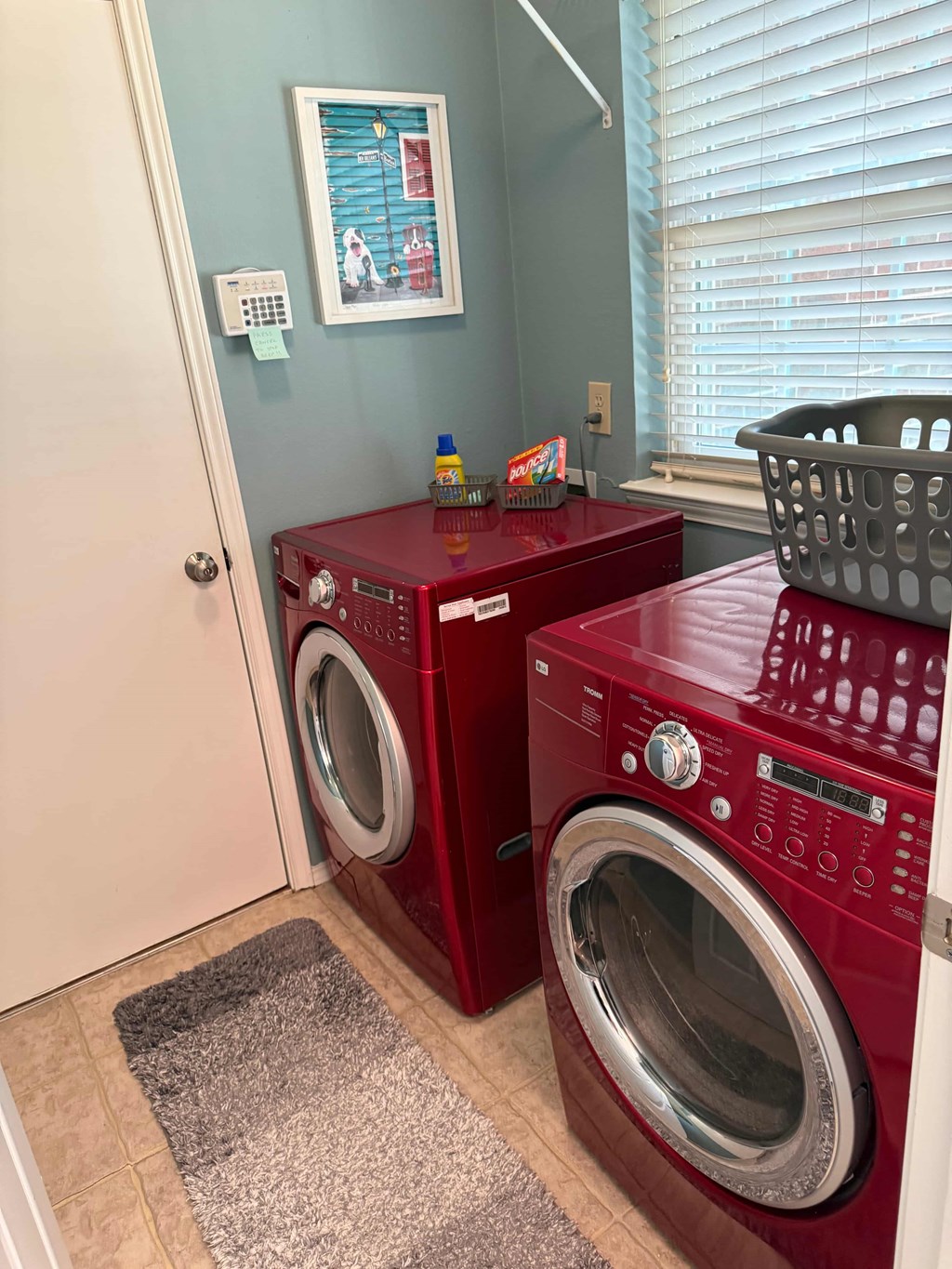 A red washing machine and dryer in a small laundry room.