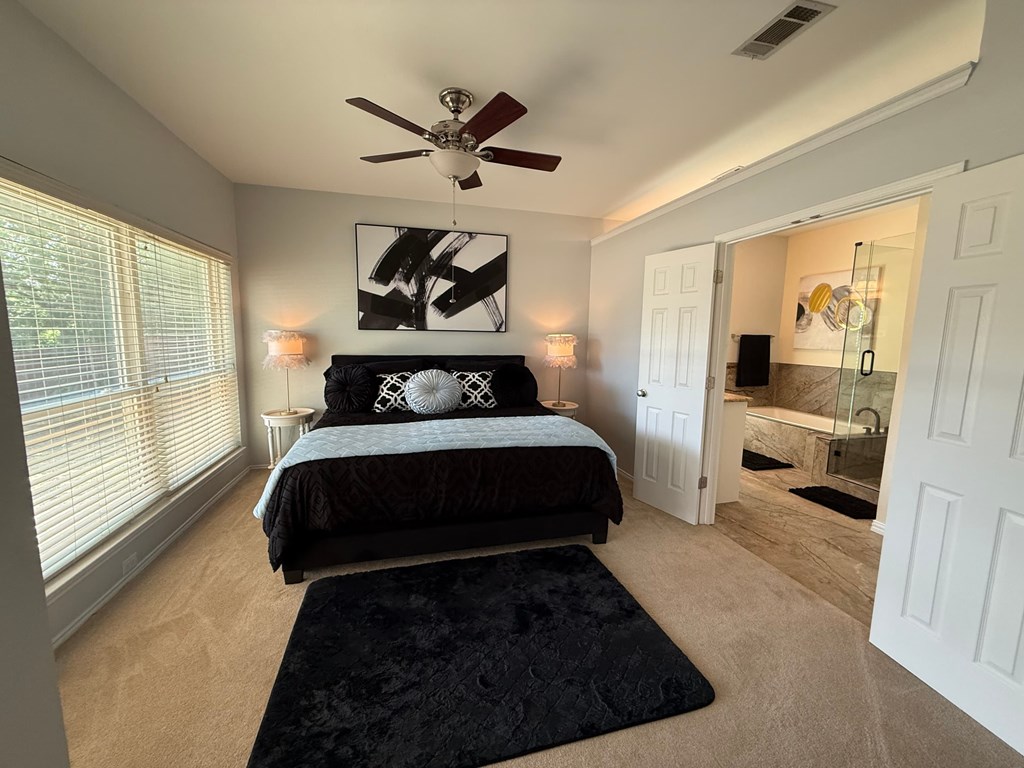 A bedroom with a bed, a ceiling fan, and a rug.