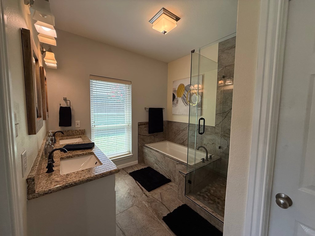 A bathroom with a sink, mirror, and shower.
