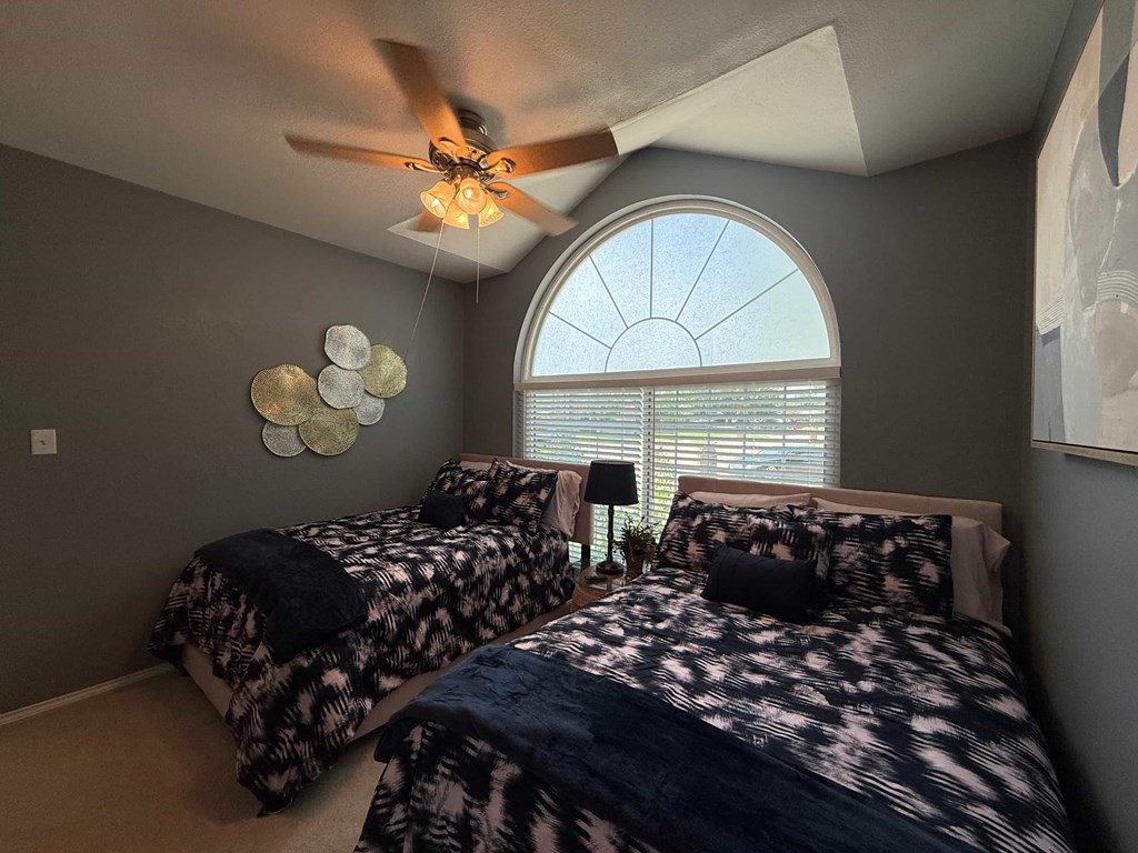 Two beds with patterned bedspreads in a room with a ceiling fan.