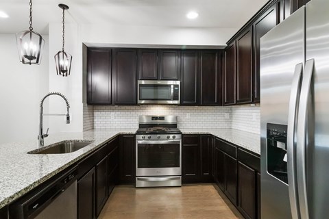 A modern kitchen with dark wood cabinets and stainless steel appliances.