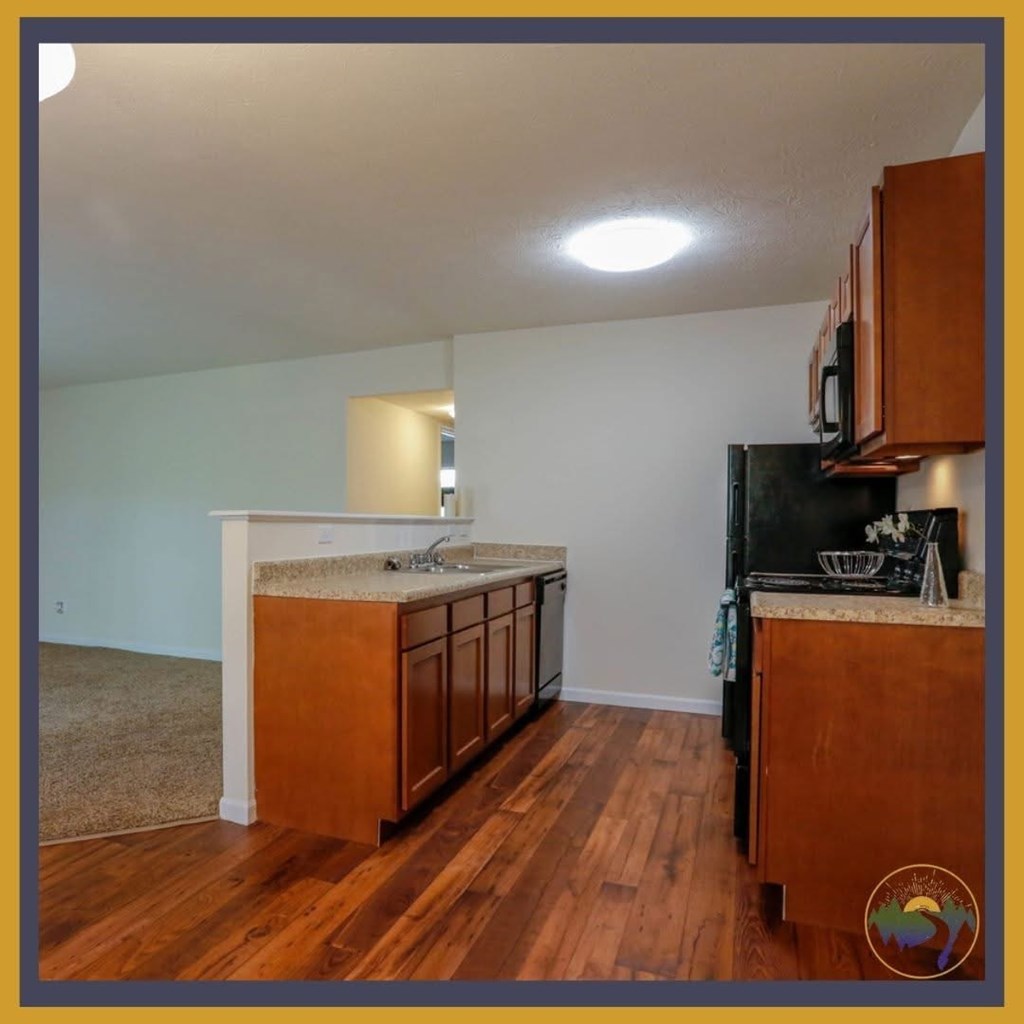 A kitchen with wooden cabinets and a black refrigerator.