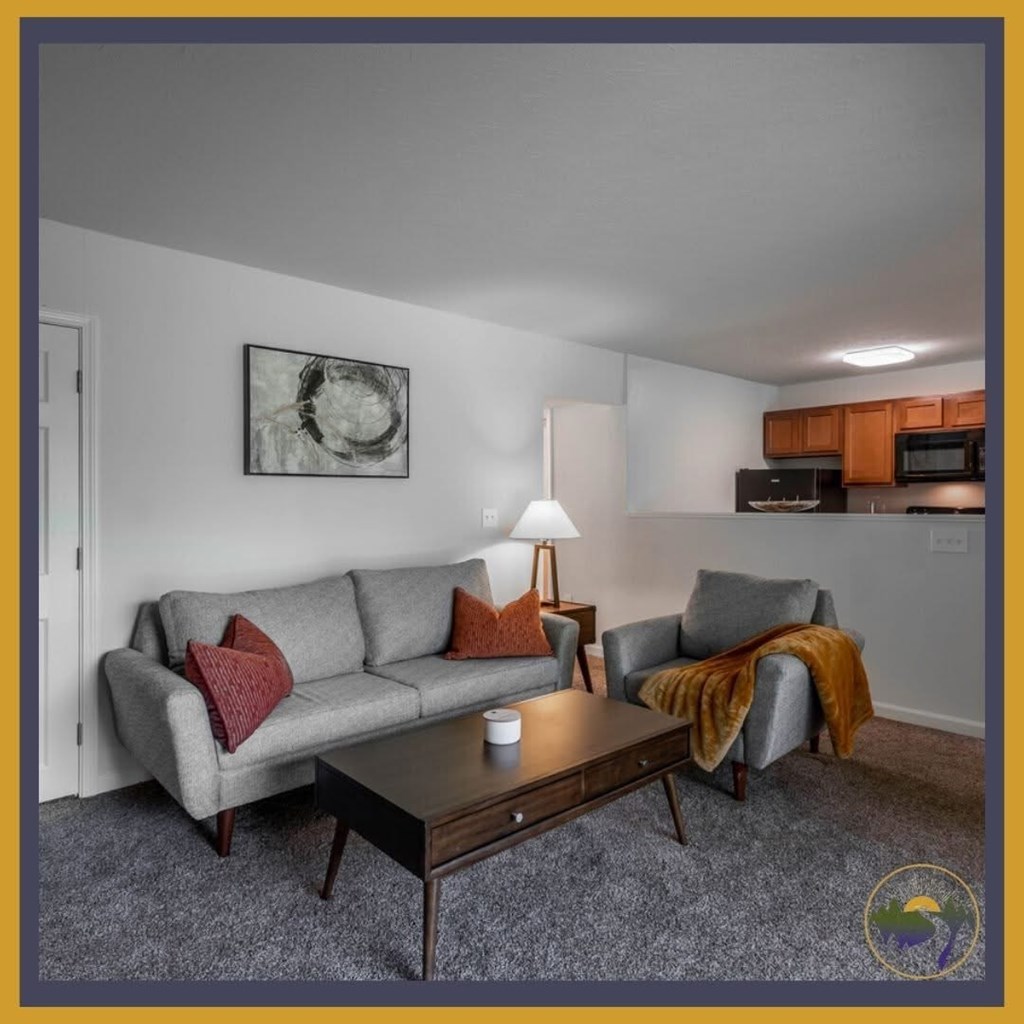 A living room with a grey couch, a coffee table, and a lamp.