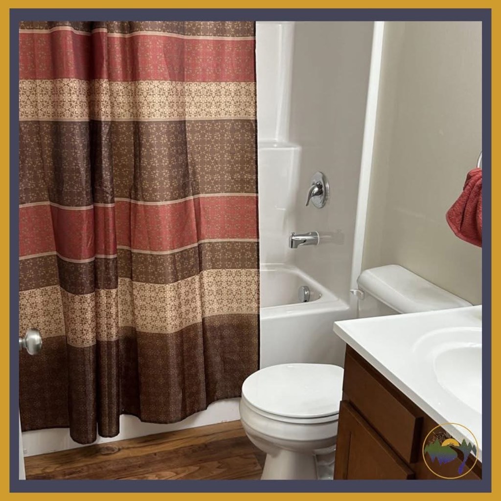 A white toilet sits under a shower curtain in a bathroom.